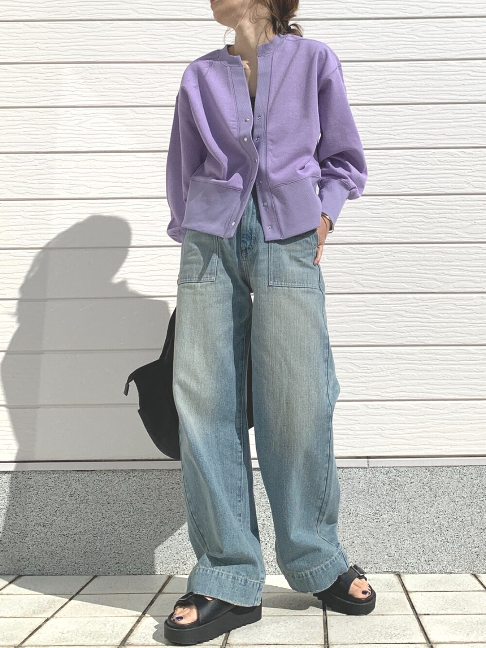 ブラック系のトートバッグ、ブルー系のデニムパンツ、ブラック系のサンダルを着用したレディースの春コーディネートの2枚目の写真
