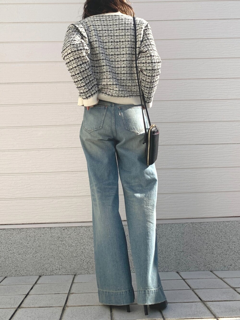 ブルー系のデニムパンツ、ホワイト系のカーディガン/ボレロ、ブラック系のショルダーバッグを着用したレディースの冬コーディネートの3枚目の写真