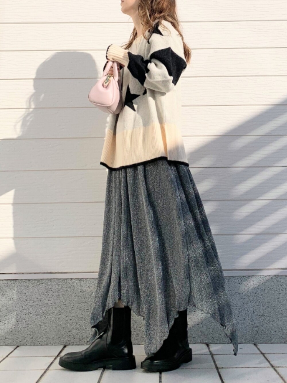 ピンク系のショルダーバッグ、ブラック系のスカート、ホワイト系のニット/セーターを着用したレディースの冬コーディネートの2枚目の写真