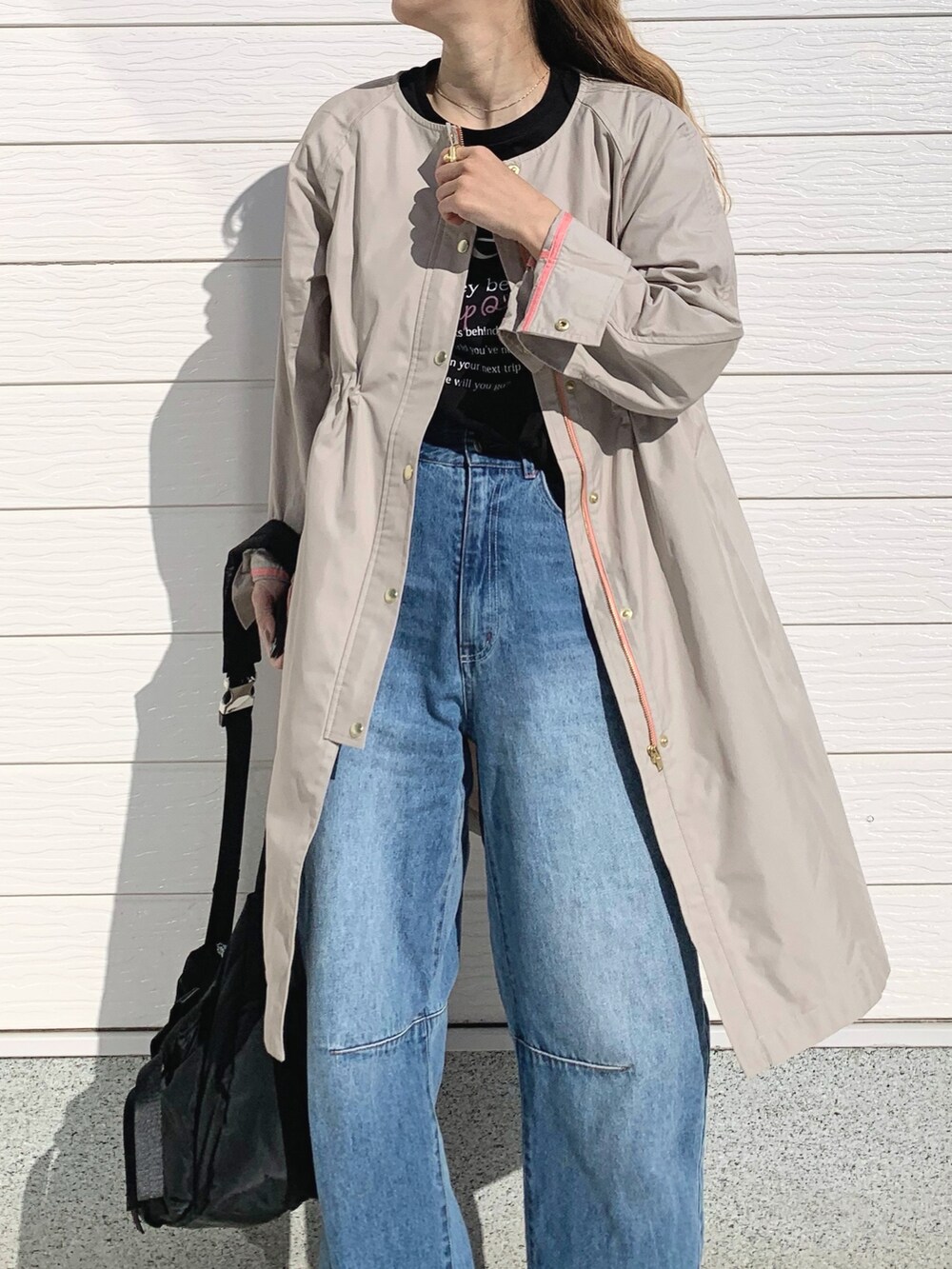 ブルー系のデニムパンツ、ブラック系のショルダーバッグ、ベージュ系のノーカラーコートを着用したレディースの春コーディネートの3枚目の写真