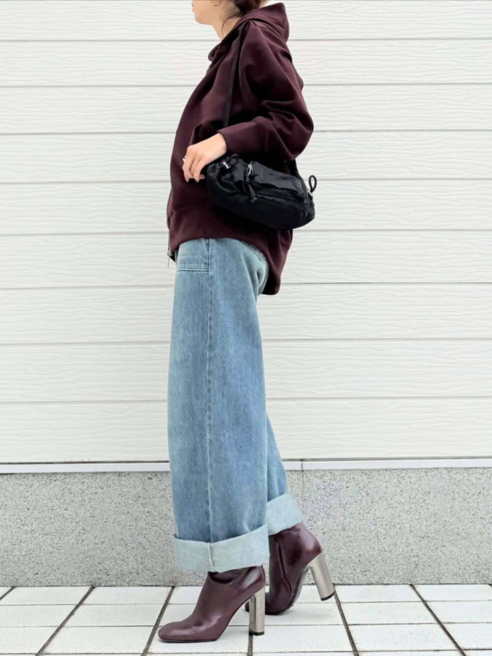 ブルー系のデニムパンツ、ブラウン系のブーツ、ブラック系のショルダーバッグを着用したレディースの秋コーディネートの2枚目の写真