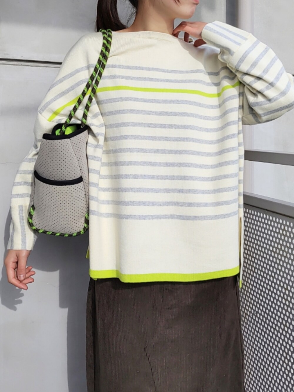 グレー系のトートバッグ、ブラウン系のスカート、ホワイト系のスニーカーを着用したレディースの冬コーディネートの3枚目の写真