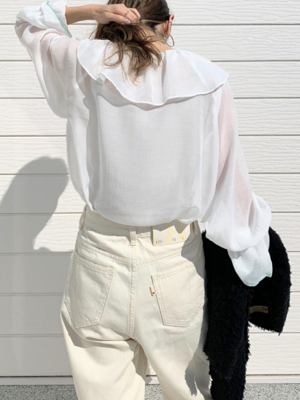 ピンク系のショルダーバッグ、ホワイト系のデニムパンツ、ブラック系のカーディガン/ボレロを着用したレディースの春コーディネートの5枚目の写真