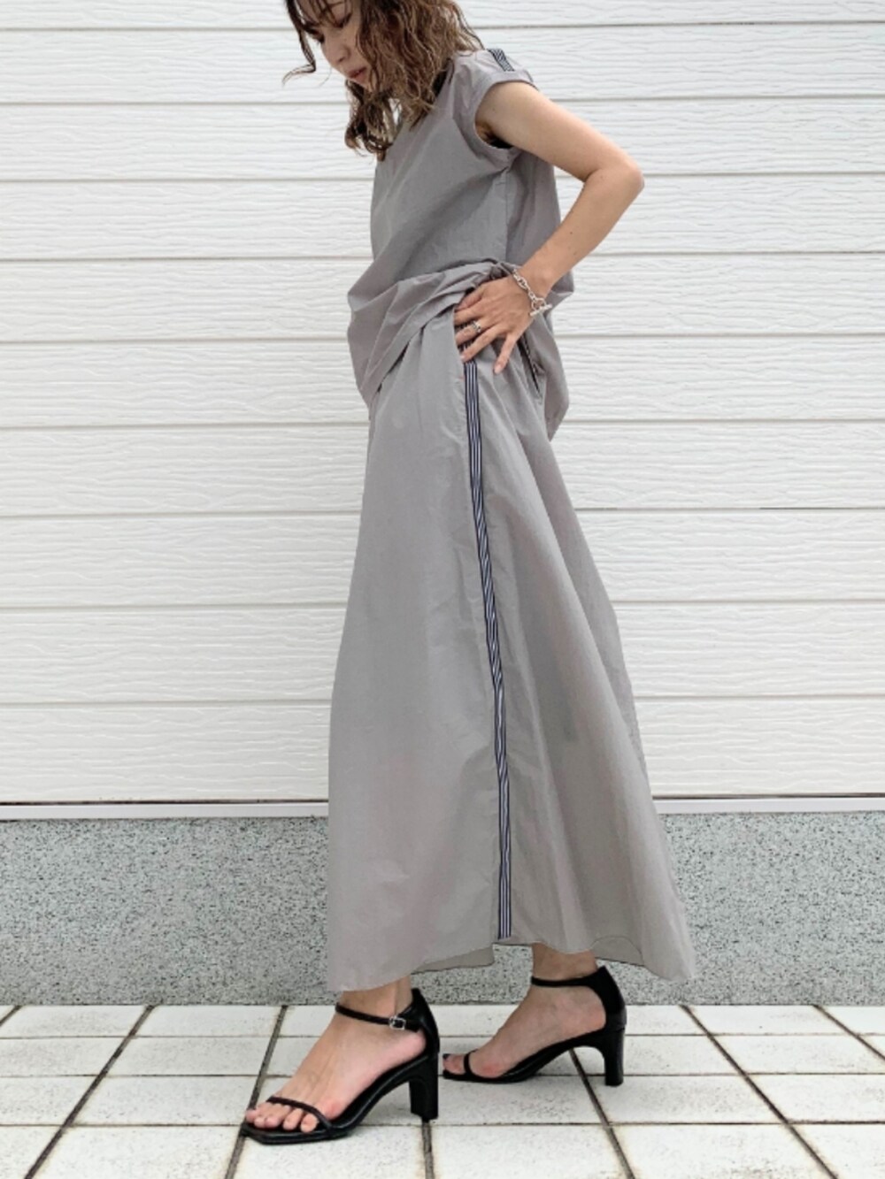 ブルー系のハンドバッグ、グレー系のTシャツ/カットソー、グレー系のスカートを着用したレディースの夏コーディネートの2枚目の写真