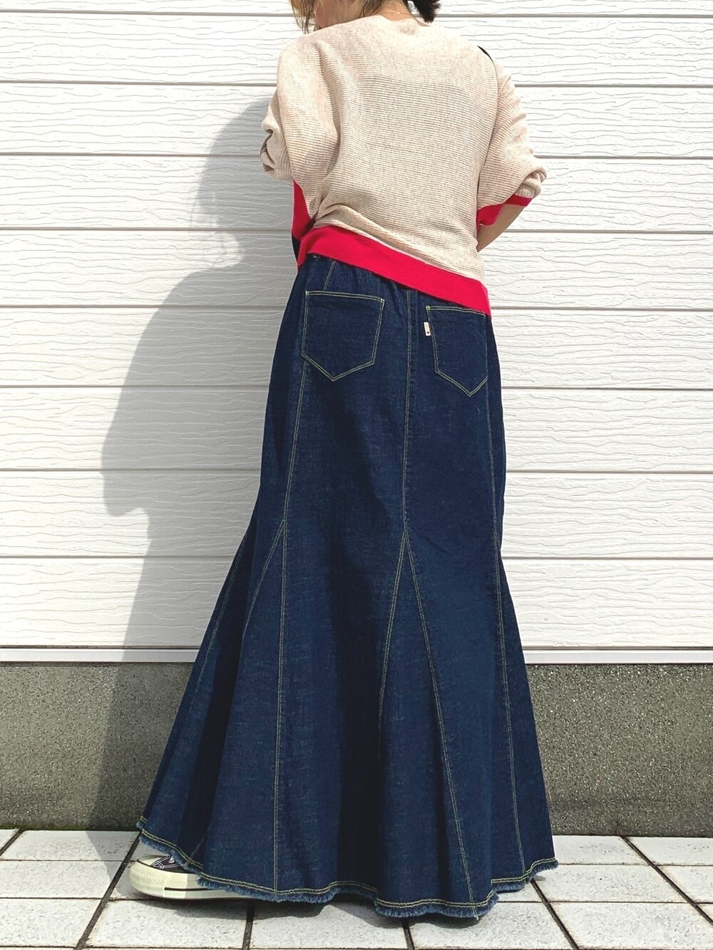 ブルー系のデニムスカート、ブラック系のスニーカー、ブラック系のショルダーバッグを着用したレディースの秋コーディネートの2枚目の写真