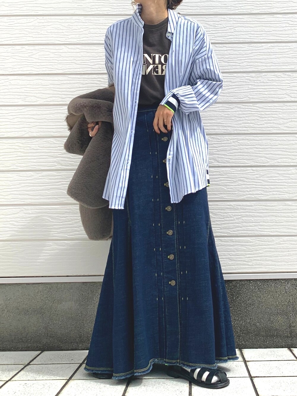 ブルー系のデニムスカート、グレー系のTシャツ/カットソー、ブラウン系のベストを着用したレディースの秋コーディネートの2枚目の写真
