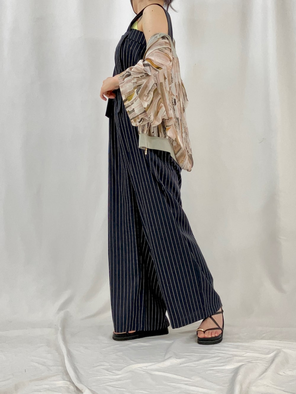 ベージュ系のブルゾン、ブルー系のサロペット/オーバーオール、ブラック系のサンダルを着用したレディースの春コーディネートの2枚目の写真