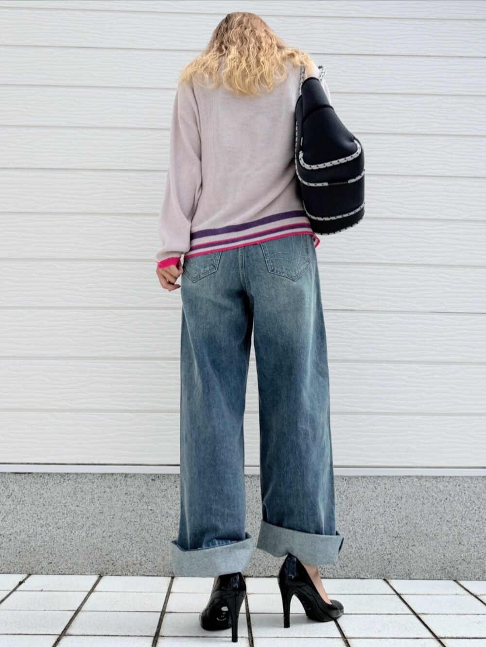 ブルー系のデニムパンツ、ブラック系のニット/セーター、ブルー系のトートバッグを着用したレディースの秋コーディネートの3枚目の写真