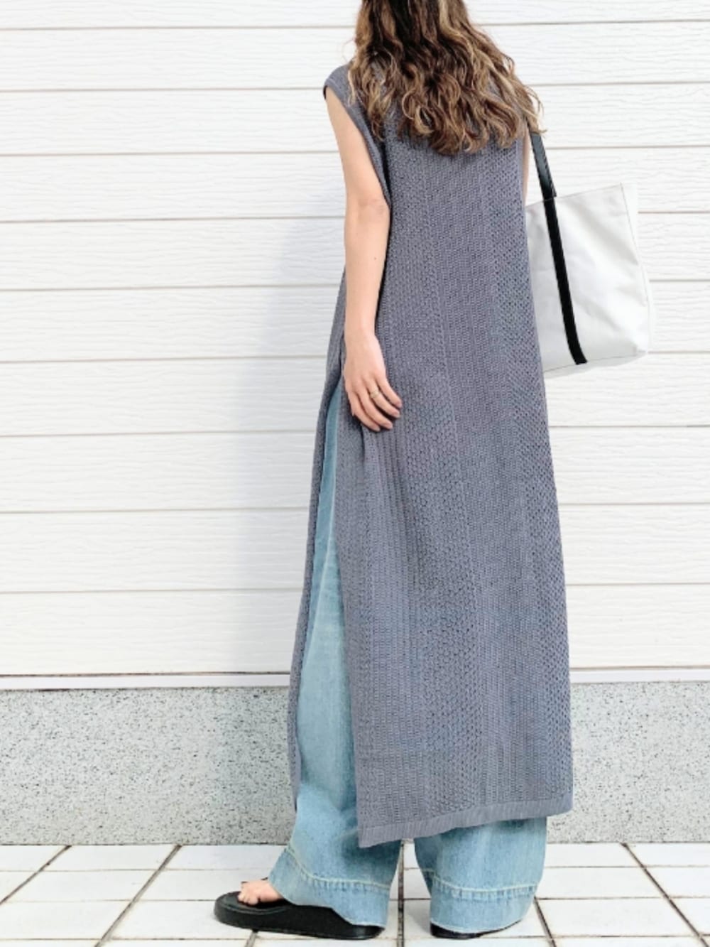 ホワイト系のトートバッグ、ブルー系のデニムパンツ、グレー系のワンピースを着用したレディースの春コーディネートの4枚目の写真