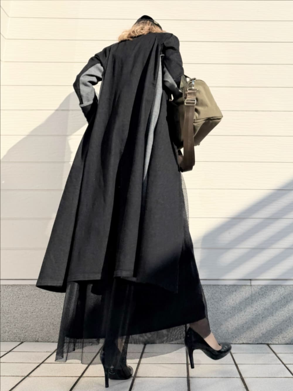 グリーン系のスカート、グリーン系のボストンバッグ、ブラック系のデニムジャケットを着用したレディースの冬コーディネートの3枚目の写真