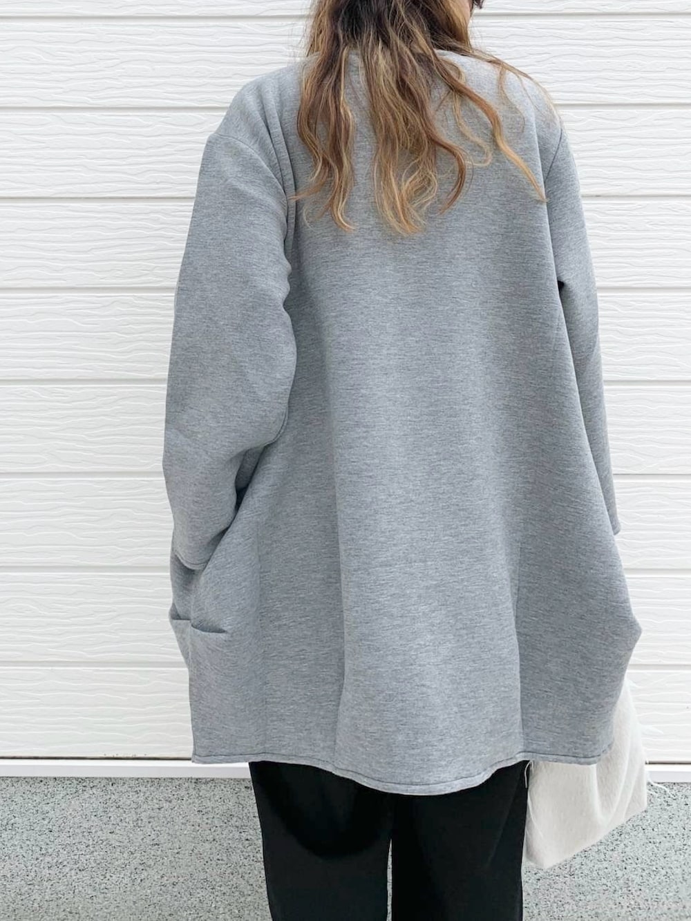 グレー系のクラッチバッグ、ホワイト系のスニーカー、ブラック系のTシャツ/カットソーを着用したレディースの秋コーディネートの3枚目の写真