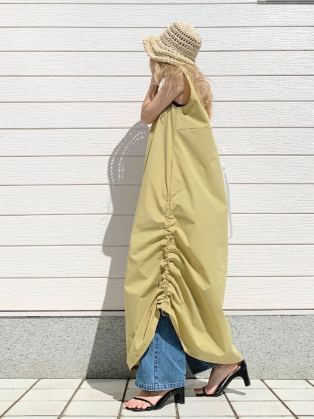 ブルー系のデニムパンツ、イエロー系のワンピース、ホワイト系のショルダーバッグを着用したレディースの春コーディネートの2枚目の写真