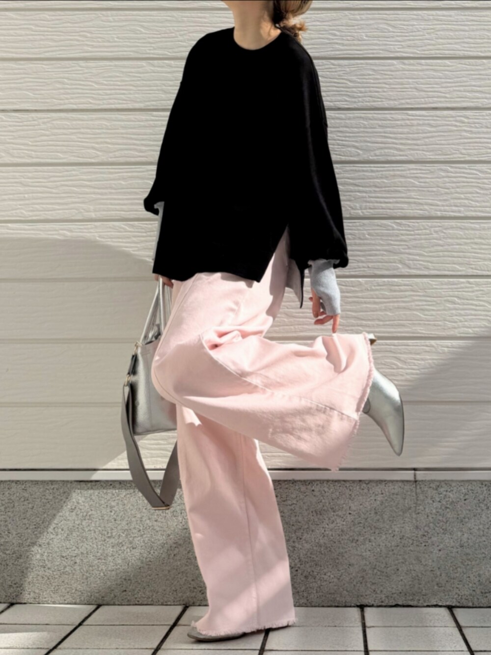 シルバー系のトートバッグ、ピンク系のデニムパンツ、ブラック系のニット/セーターを着用したレディースの冬コーディネートの2枚目の写真