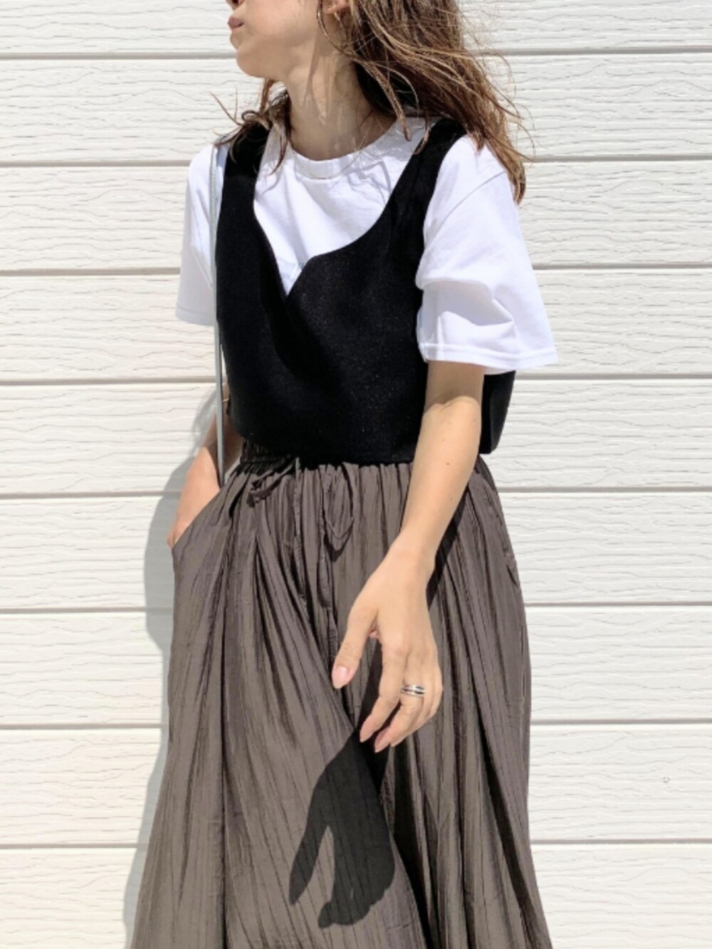 シルバー系のショルダーバッグ、ブラック系のベスト、ホワイト系のTシャツ/カットソーを着用したレディースの夏コーディネートの4枚目の写真