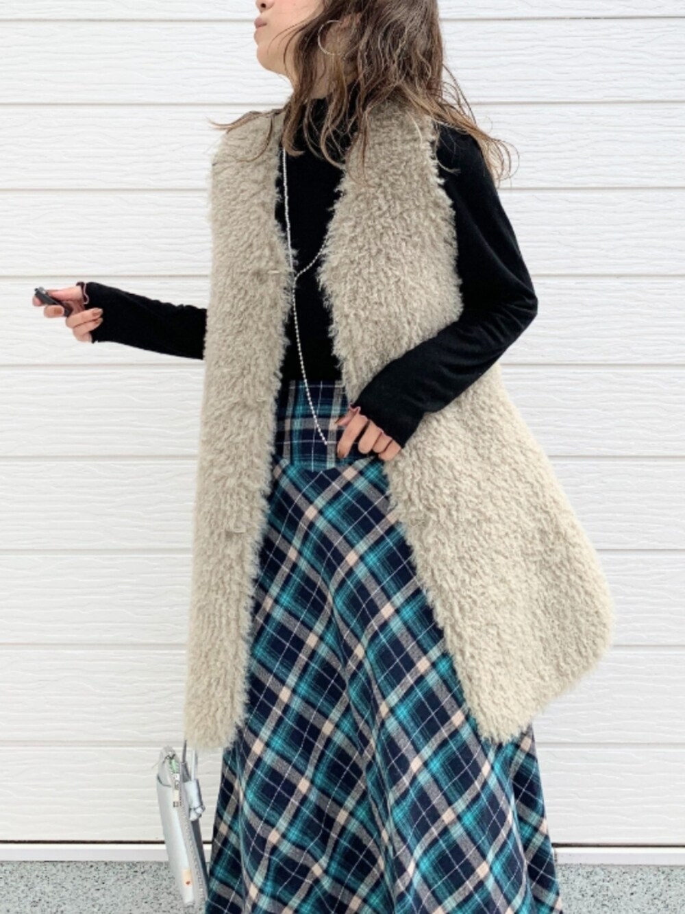 ベージュ系のベスト、シルバー系のショルダーバッグ、ブルー系のスカートを着用したレディースの秋コーディネートの3枚目の写真