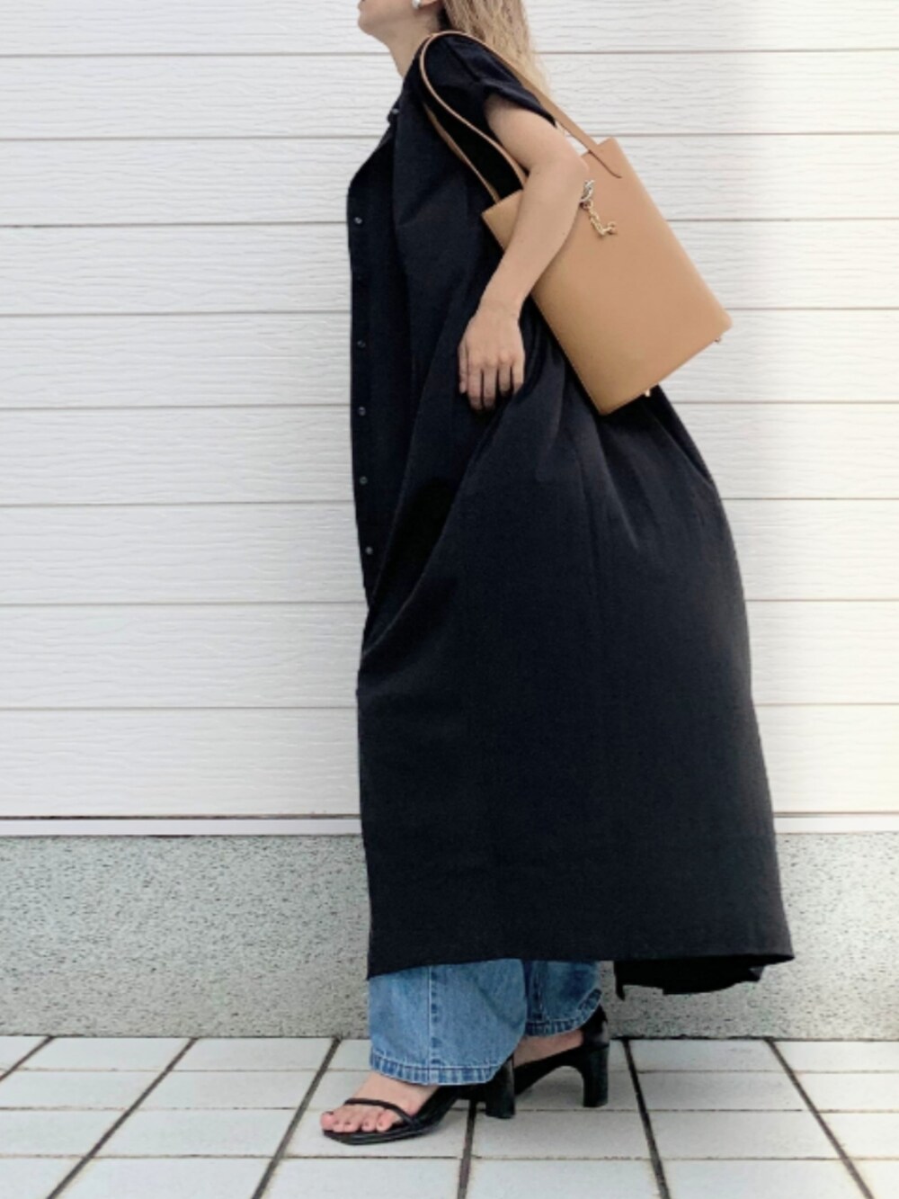 グレー系のトートバッグ、ブルー系のデニムパンツ、ブラック系のシャツワンピースを着用したレディースの夏コーディネートの2枚目の写真