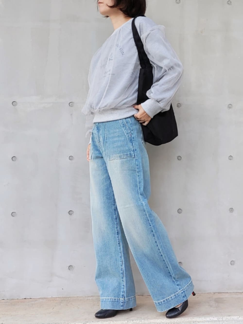 ブルー系のデニムパンツ、ブラック系のトートバッグ、グレー系のスウェットを着用したレディースの秋コーディネートの2枚目の写真
