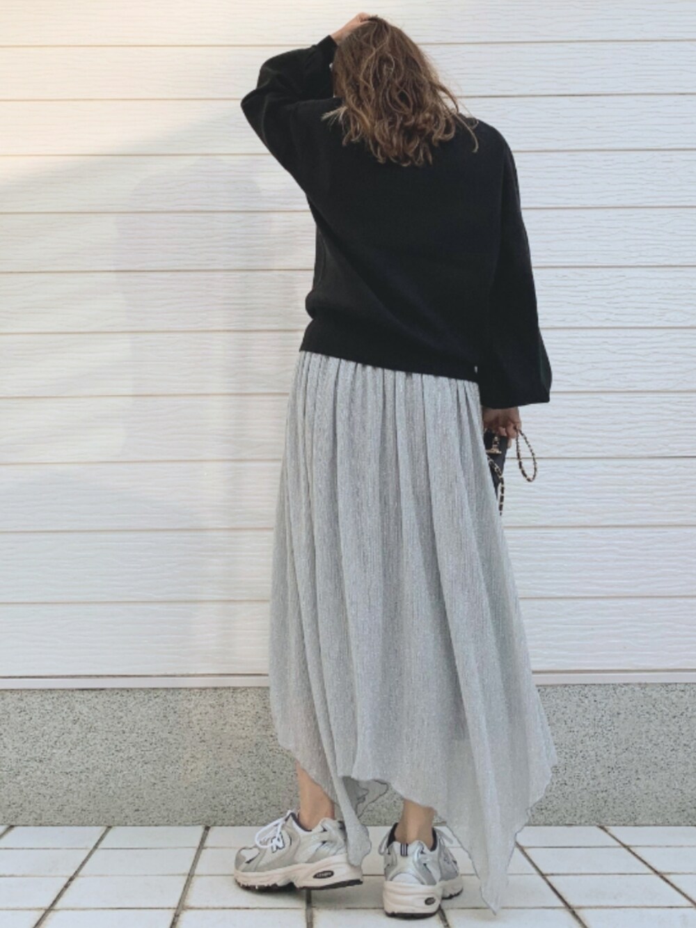 シルバー系のスカート、シルバー系のスニーカー、ブラック系のニット/セーターを着用したレディースの冬コーディネートの2枚目の写真