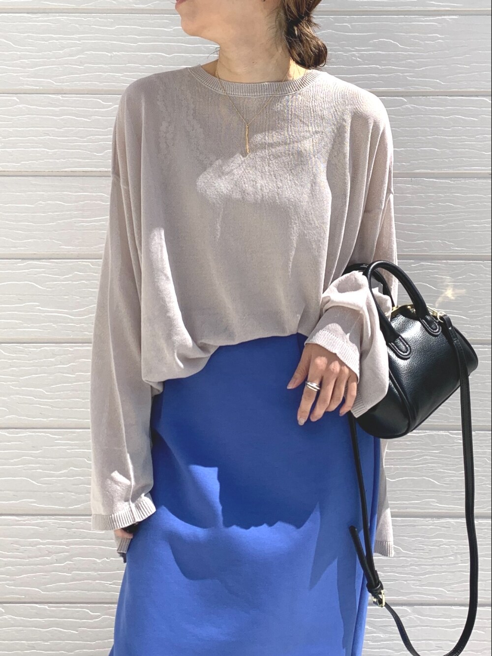 ブルー系のスカート、ブラック系のショルダーバッグ、ベージュ系のニット/セーターを着用したレディースの春コーディネートの3枚目の写真