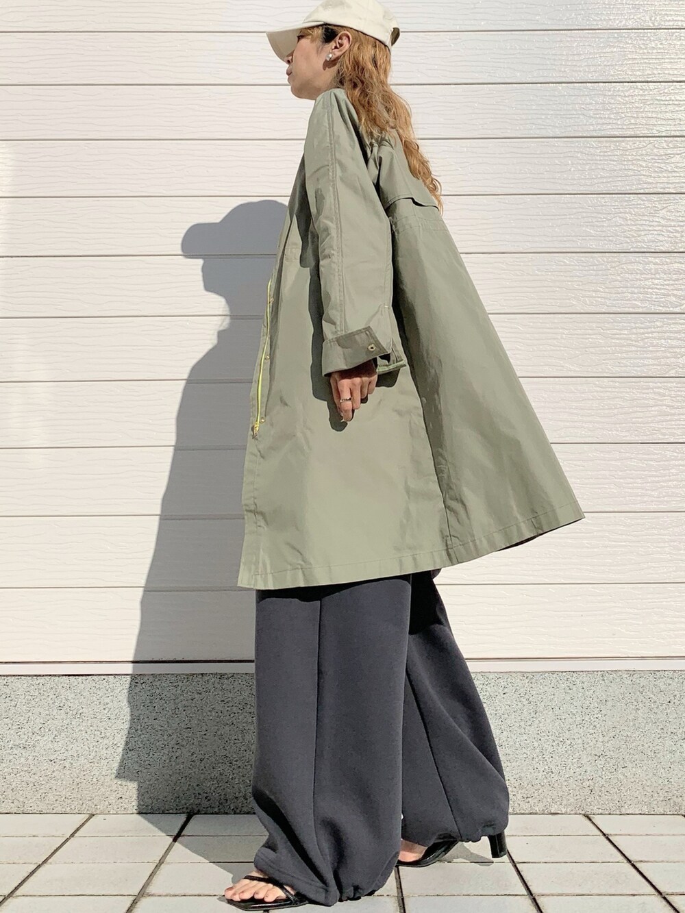 グリーン系のノーカラーコート、グリーン系のニット/セーター、ホワイト系のショルダーバッグを着用したレディースの春コーディネートの2枚目の写真