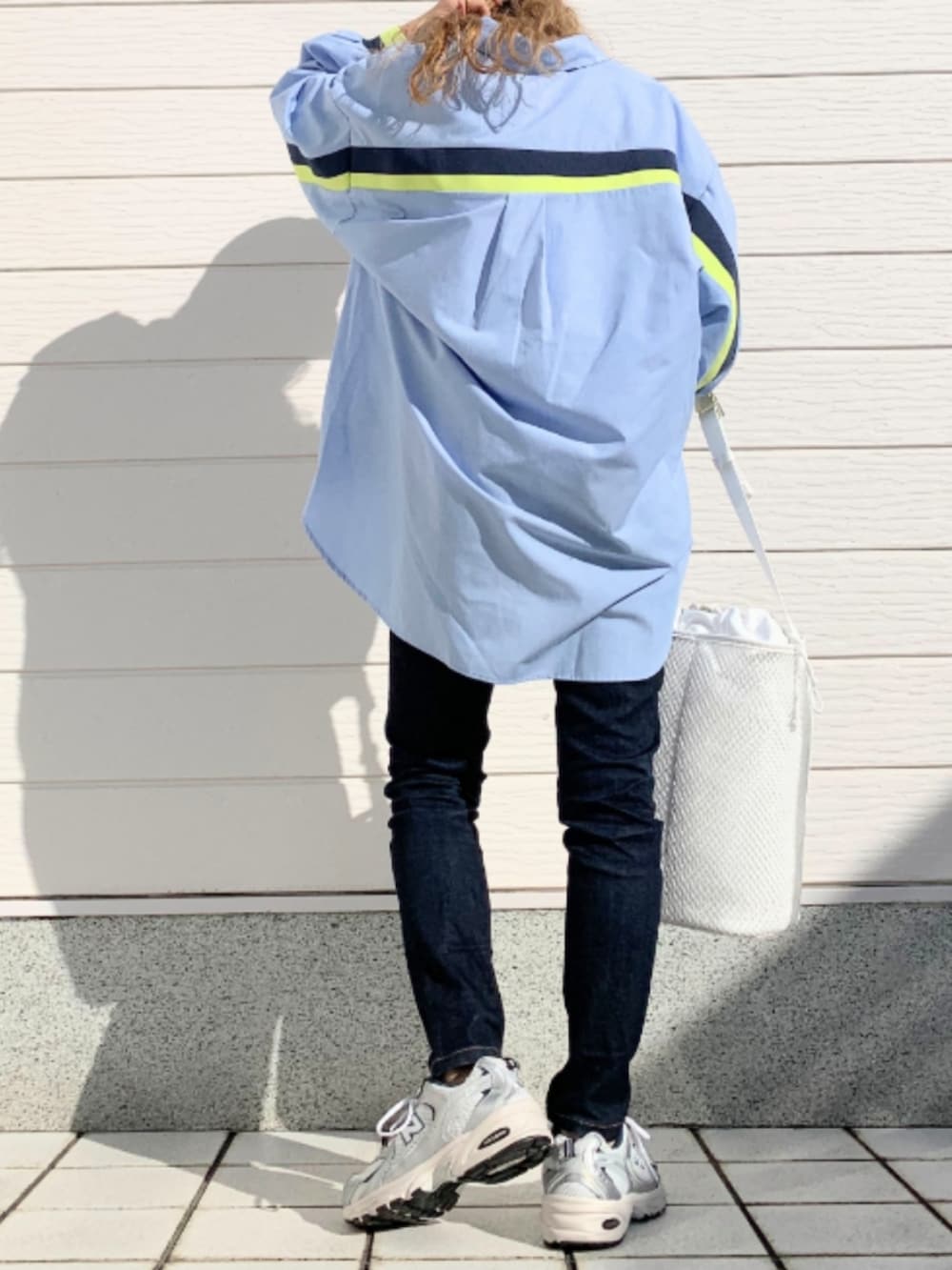 ブルー系のデニムパンツ、シルバー系のスニーカー、ホワイト系のショルダーバッグを着用したレディースの冬コーディネートの2枚目の写真