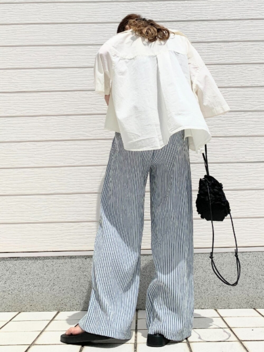 ブラック系のクラッチバッグ、ブラック系のタンクトップ、ホワイト系のシャツ/ブラウスを着用したレディースの夏コーディネートの3枚目の写真