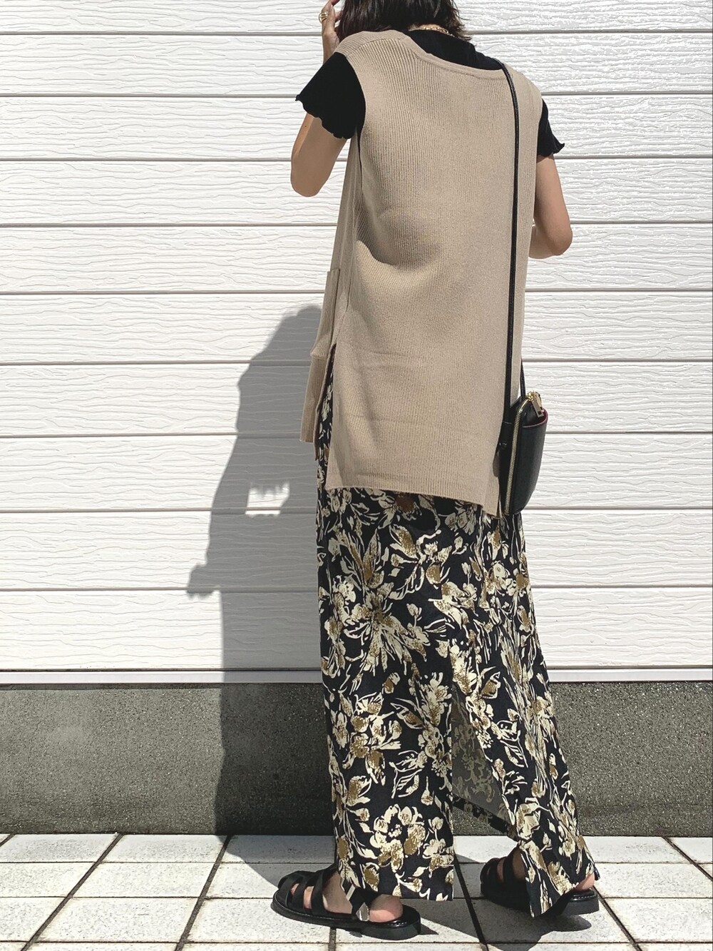 ブラック系のサンダル、ベージュ系のベスト、ブラック系のショルダーバッグを着用したレディースの夏コーディネートの2枚目の写真