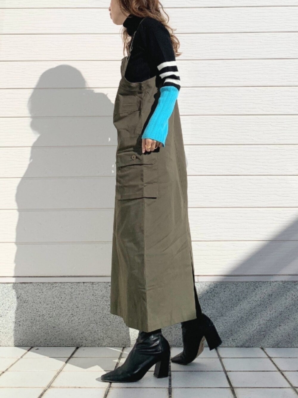 ブラック系のニット/セーター、グレー系のショルダーバッグ、グリーン系のジャンパースカートを着用したレディースの秋コーディネートの2枚目の写真