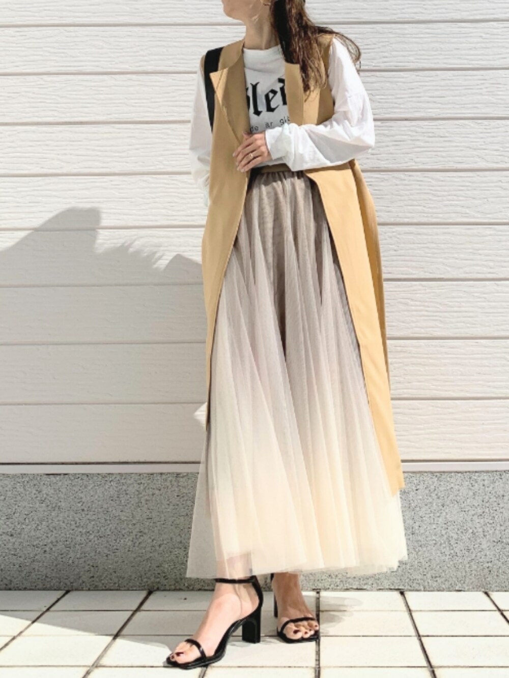 ホワイト系のTシャツ/カットソー、ブラック系のトートバッグ、ゴールド系のスカートを着用したレディースの春コーディネートの2枚目の写真