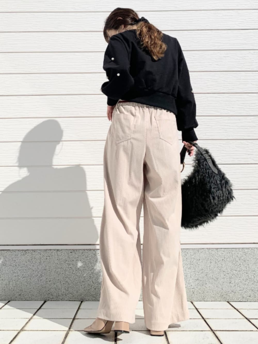 グレー系のハンドバッグ、ブラック系のスウェット、ベージュ系のその他パンツを着用したレディースの秋コーディネートの3枚目の写真