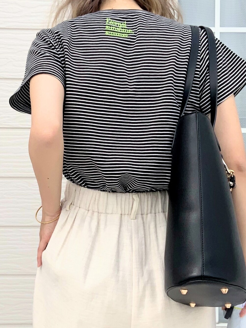 ブラック系のTシャツ/カットソー、ホワイト系のその他パンツ、ブラック系のトートバッグを着用したレディースの春コーディネートの4枚目の写真