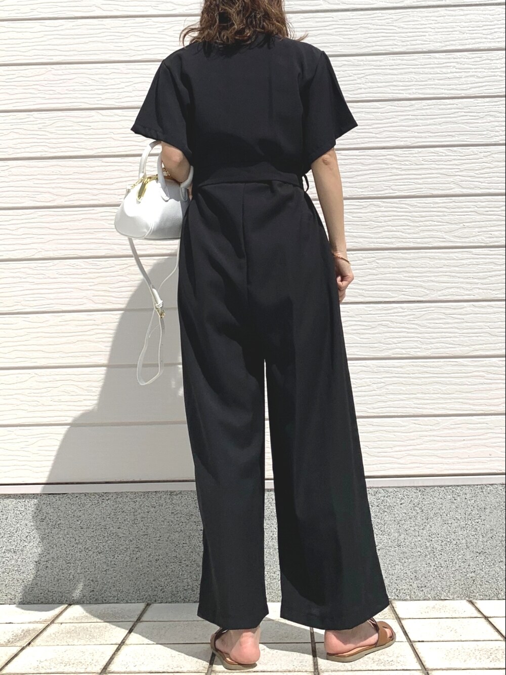 イエロー系のサンダル、ブラック系のつなぎ/オールインワン、ホワイト系のショルダーバッグを着用したレディースの春コーディネートの4枚目の写真