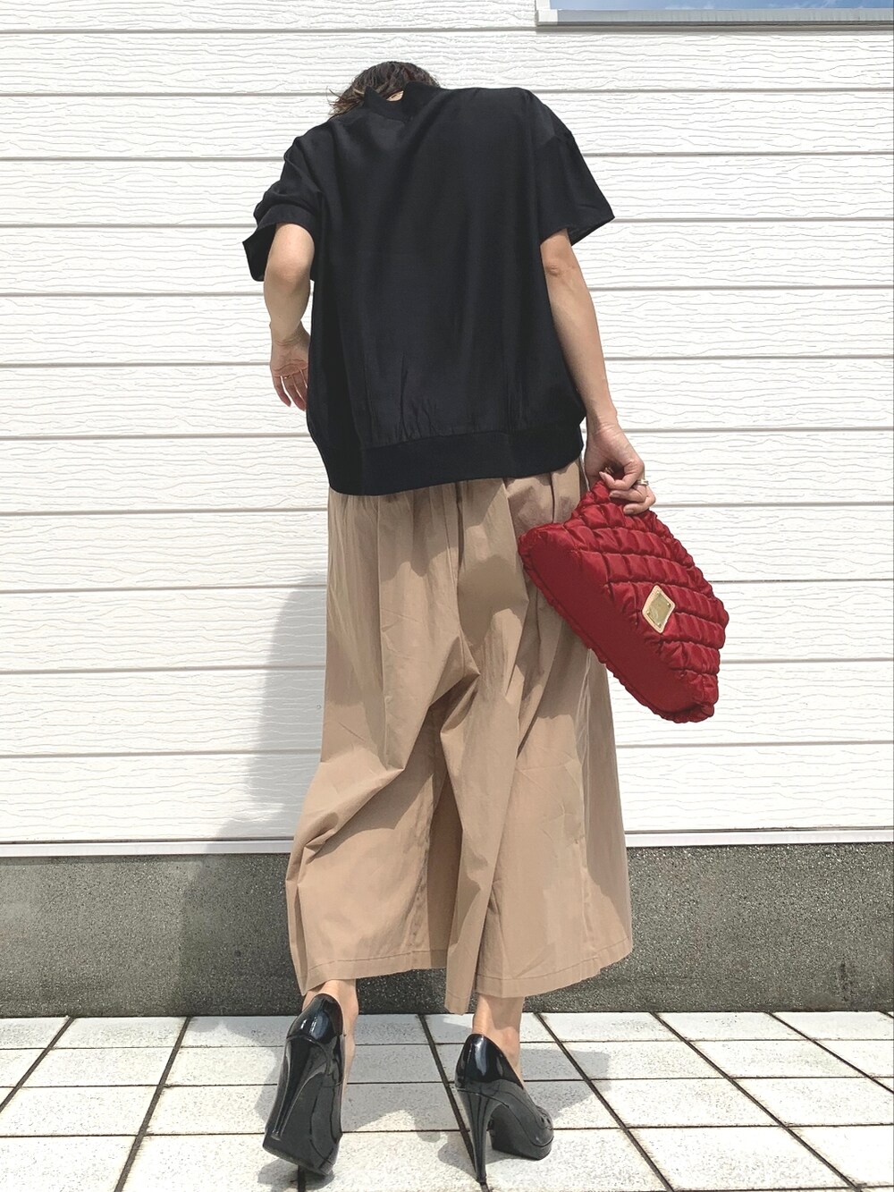 レッド系のショルダーバッグ、ベージュ系のその他パンツ、ブラック系のTシャツ/カットソーを着用したレディースの夏コーディネートの2枚目の写真
