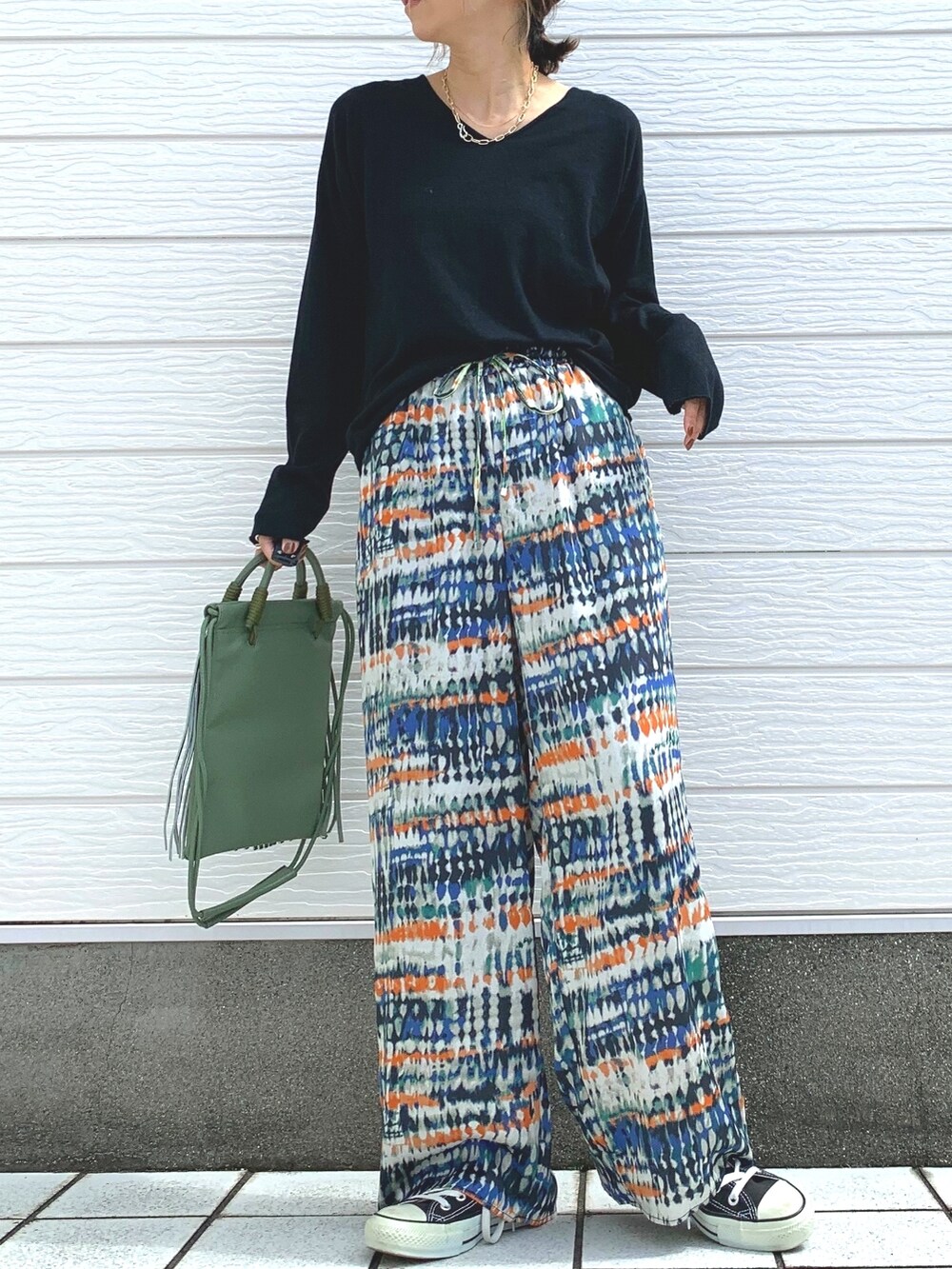 グリーン系のショルダーバッグ、ブラック系のスニーカー、ブラック系のTシャツ/カットソーを着用したレディースの秋コーディネートの2枚目の写真