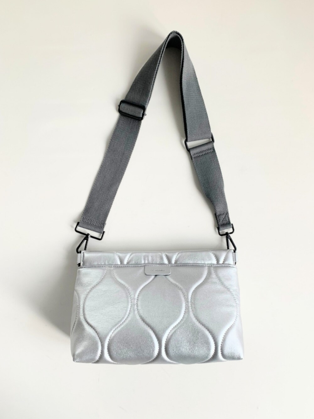 シルバー系のクラッチバッグ、ゴールド系のスカート、ホワイト系のワンピースを着用したレディースの春コーディネートの4枚目の写真