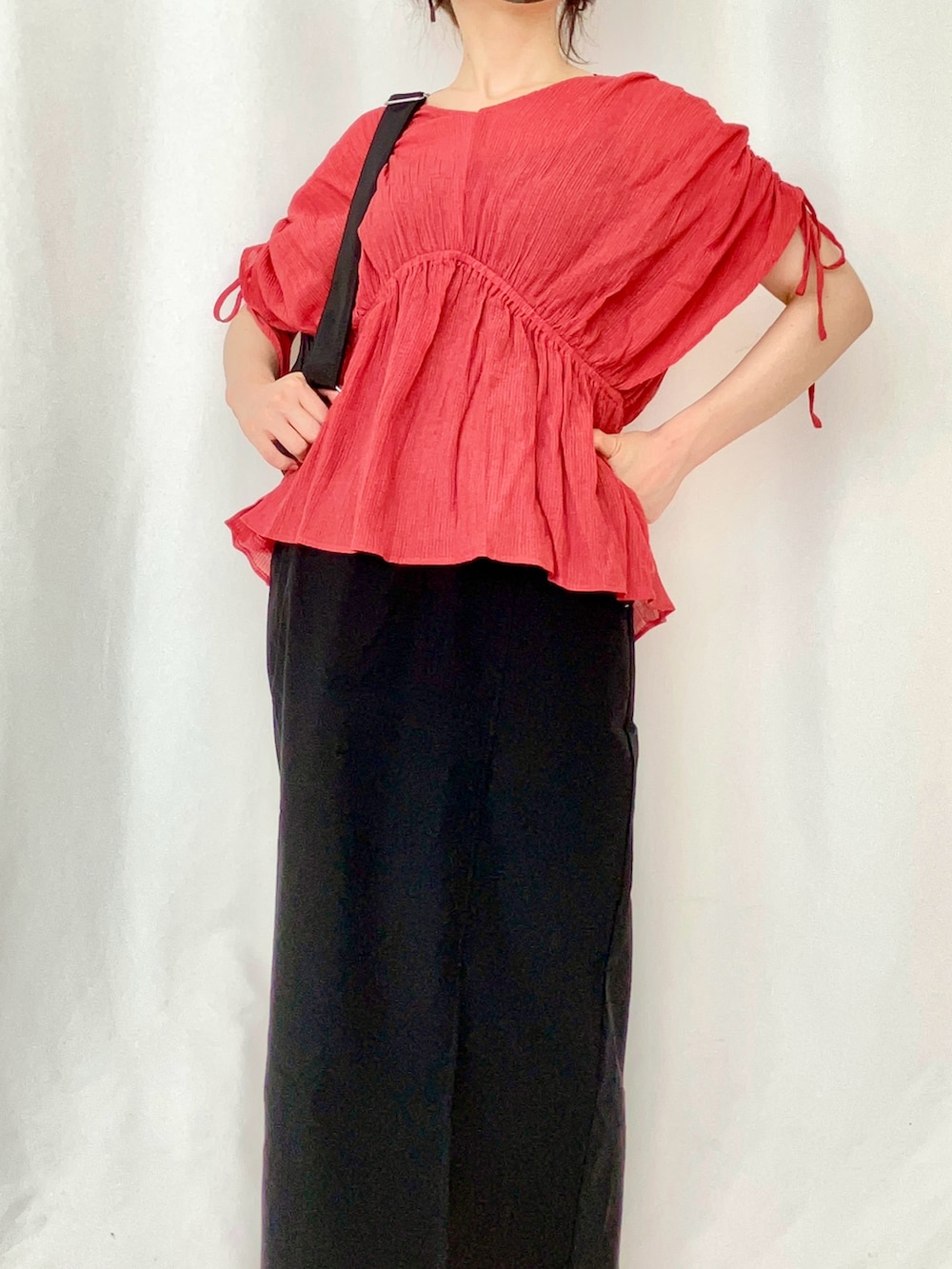 レッド系のシャツ/ブラウス、ブラック系のスカート、ブラック系のバックパック/リュックを着用したレディースの夏コーディネートの3枚目の写真
