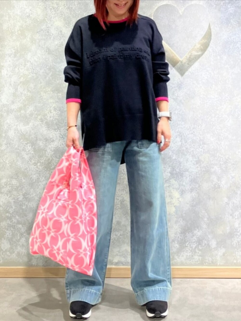 ブルー系のデニムパンツ、グレー系のブーツ、ピンク系のエコバッグ/サブバッグを着用したレディースの秋コーディネートの2枚目の写真