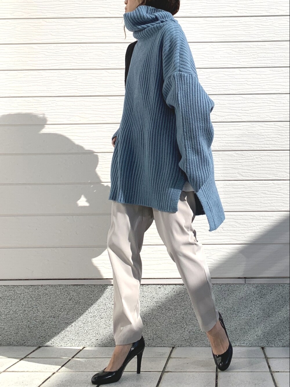 ホワイト系のその他パンツ、ブラック系のショルダーバッグ、ブルー系のニット/セーターを着用したレディースの冬コーディネートの2枚目の写真