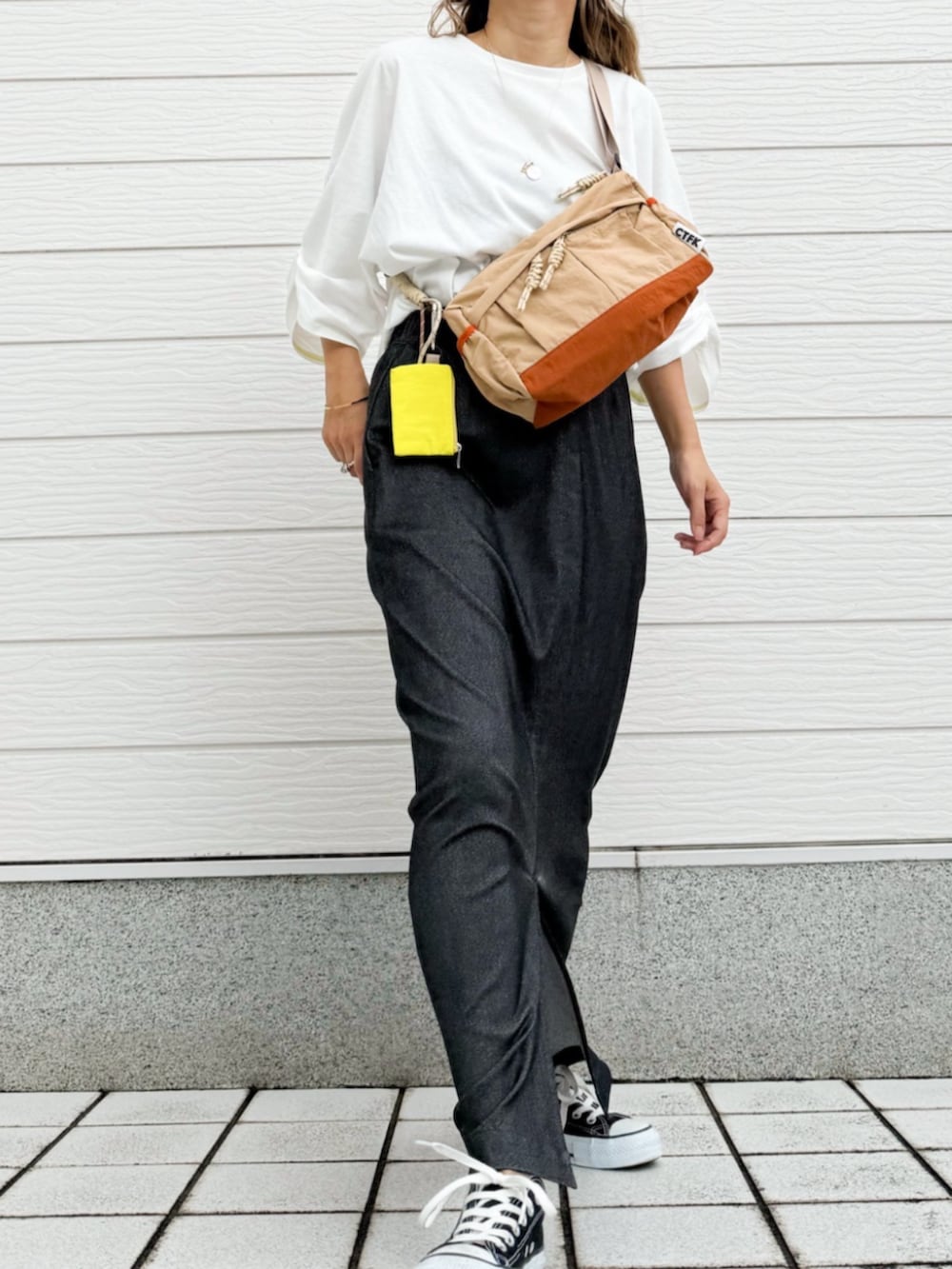 ベージュ系のショルダーバッグ、ホワイト系のTシャツ/カットソー、グレー系のスカートを着用したレディースの秋コーディネートの2枚目の写真