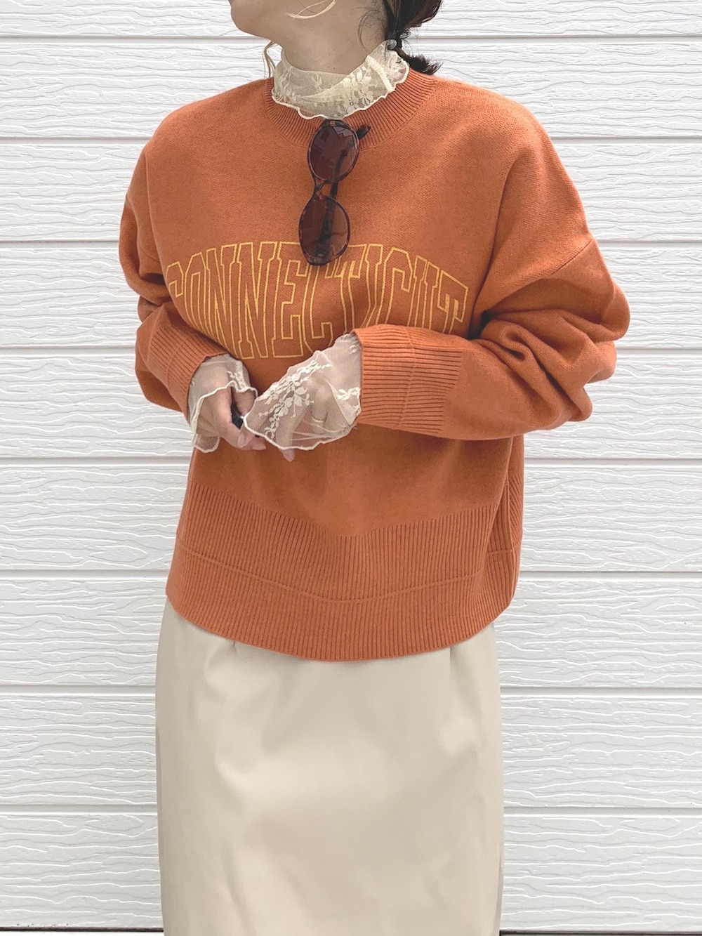 オレンジ系のニット/セーター、ベージュ系のTシャツ/カットソー、ベージュ系のスカートを着用したレディースの秋コーディネートの3枚目の写真