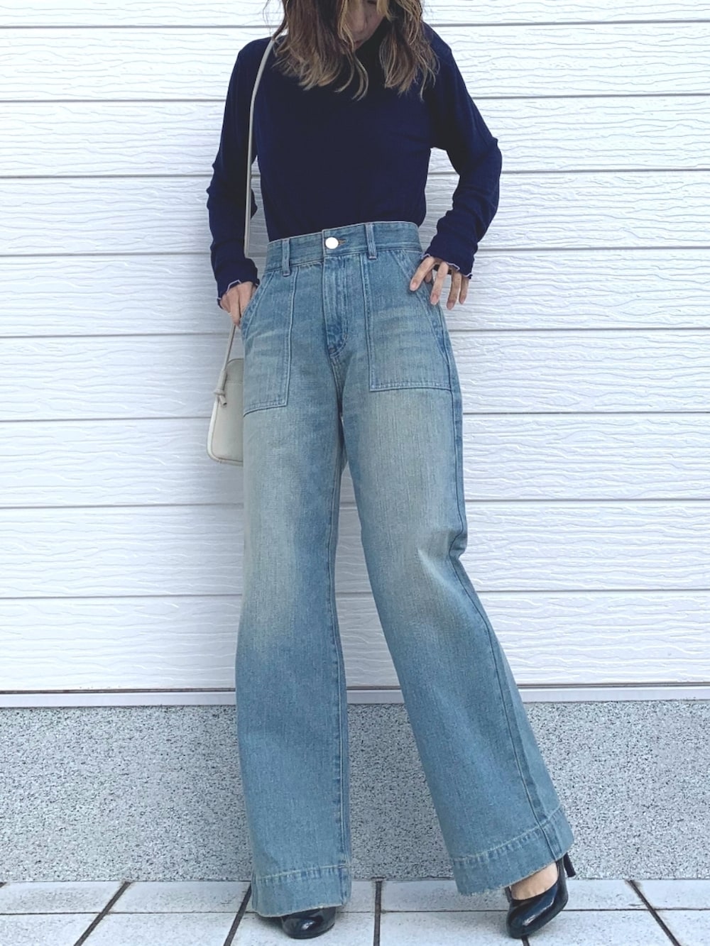 ホワイト系のショルダーバッグ、ブルー系のTシャツ/カットソー、ブルー系のデニムパンツを着用したレディースの冬コーディネートの3枚目の写真