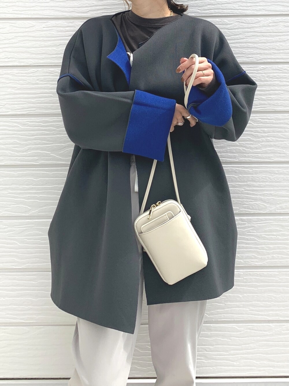 シルバー系のスニーカー、ホワイト系のその他パンツ、ブラック系のショルダーバッグを着用したレディースの秋コーディネートの2枚目の写真