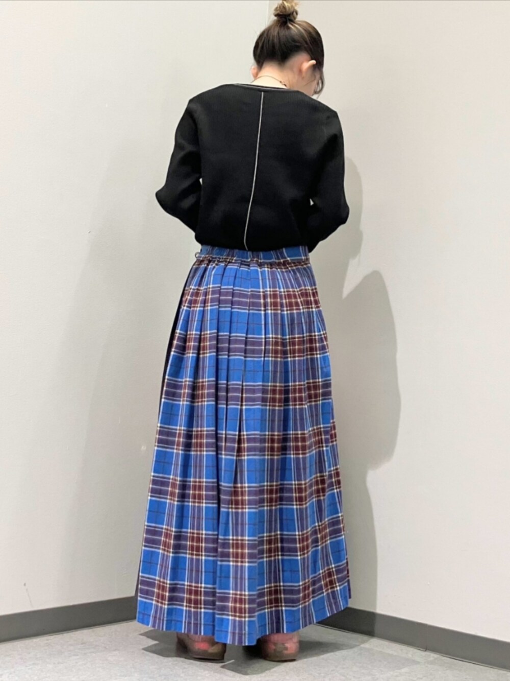 ブルー系のスカート、ブラック系のニット/セーター、ピンク系のボストンバッグを着用したレディースの秋コーディネートの2枚目の写真