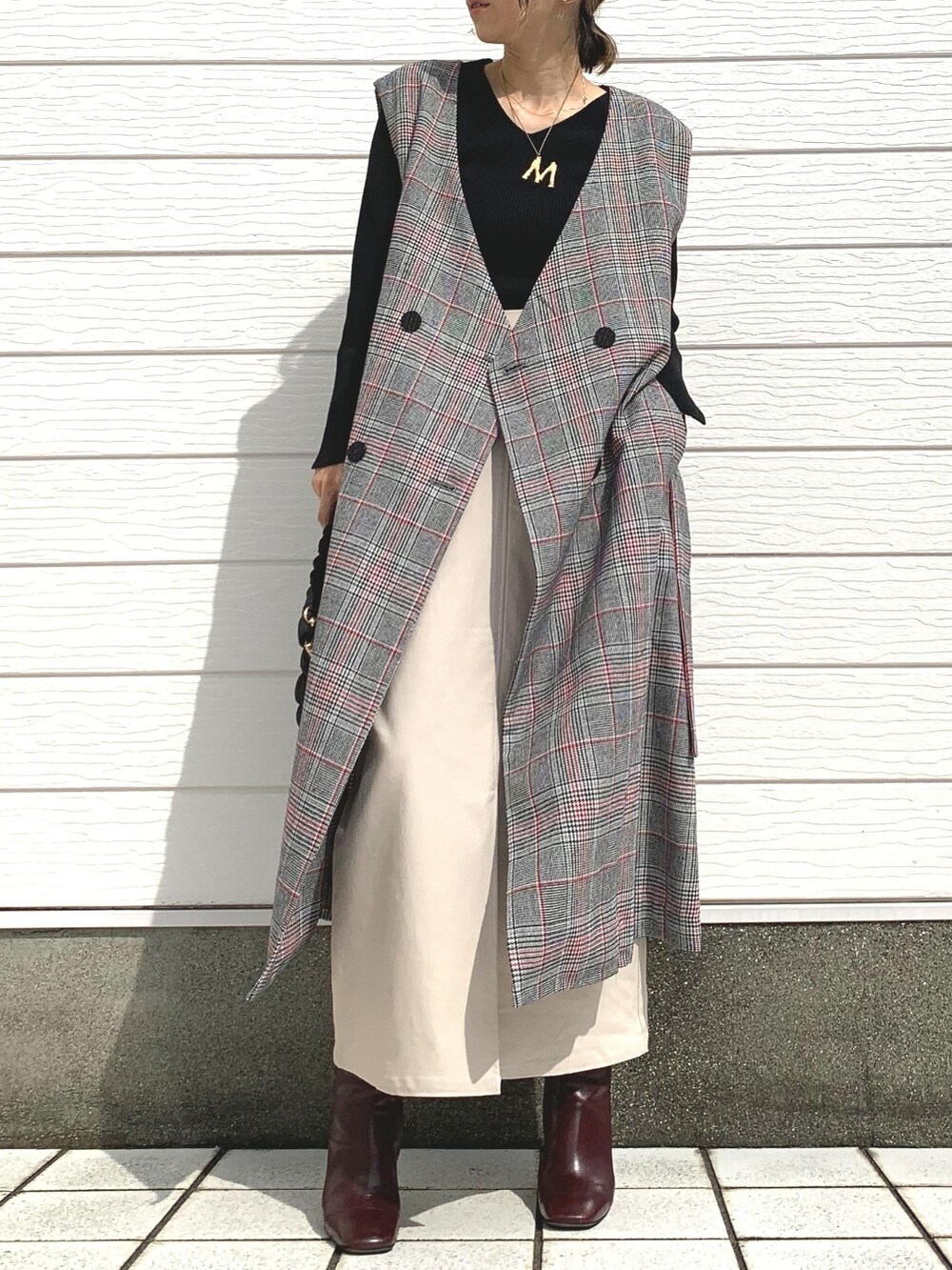 ブラック系のトレンチコート、ブラック系のショルダーバッグ、ブラウン系のブーツを着用したレディースの秋コーディネートの2枚目の写真