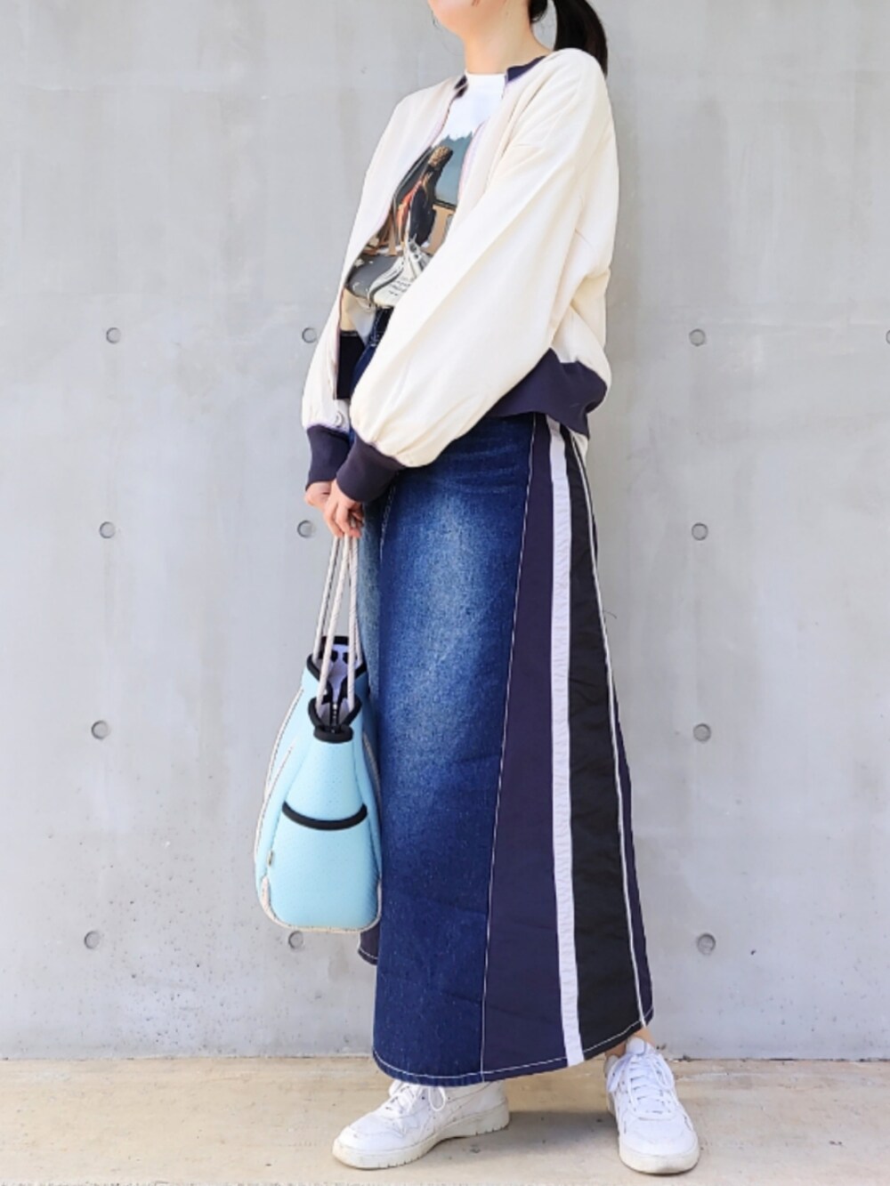 ブルー系のトートバッグ、ブルー系のデニムスカート、ホワイト系のスニーカーを着用したレディースの冬コーディネートの3枚目の写真