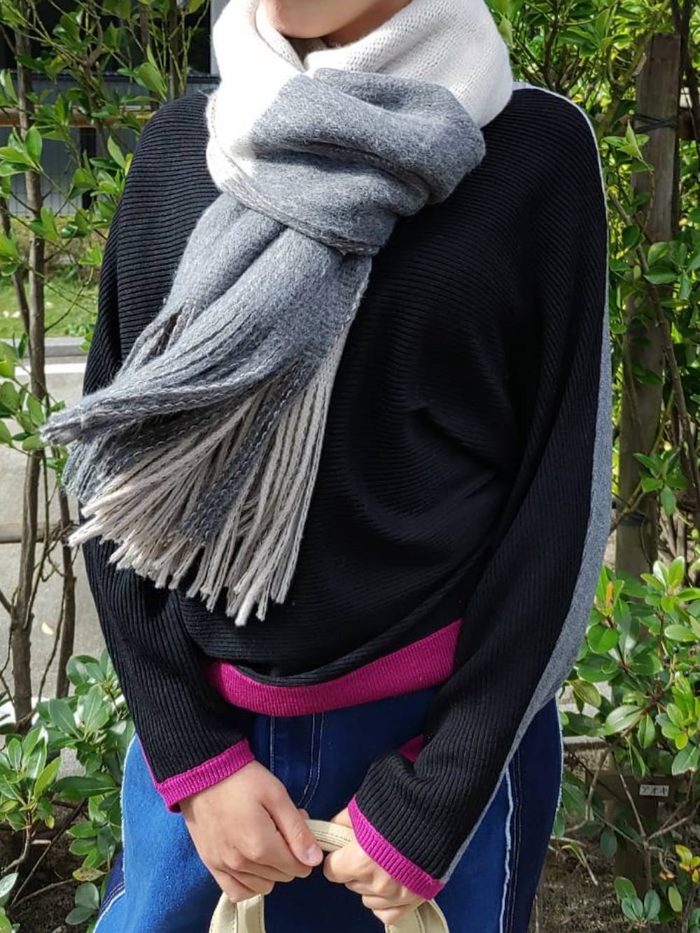 ベージュ系のトートバッグ、ブラック系のニット/セーター、ブラック系のスニーカーを着用したレディースの秋コーディネートの3枚目の写真