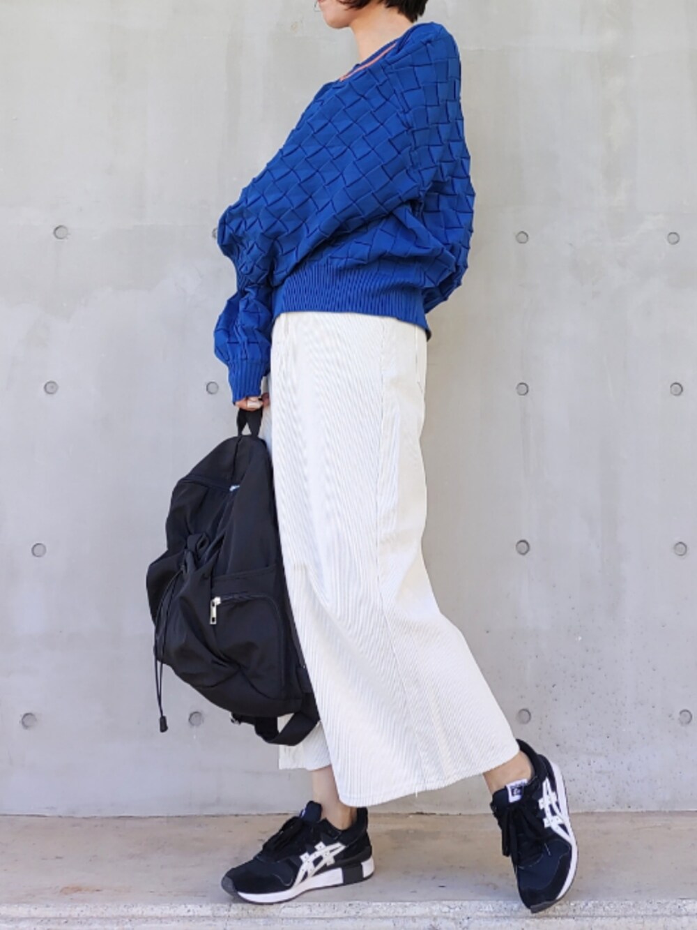 ブラック系のバックパック/リュック、ホワイト系のスカート、ブラック系のスニーカーを着用したレディースの冬コーディネートの2枚目の写真