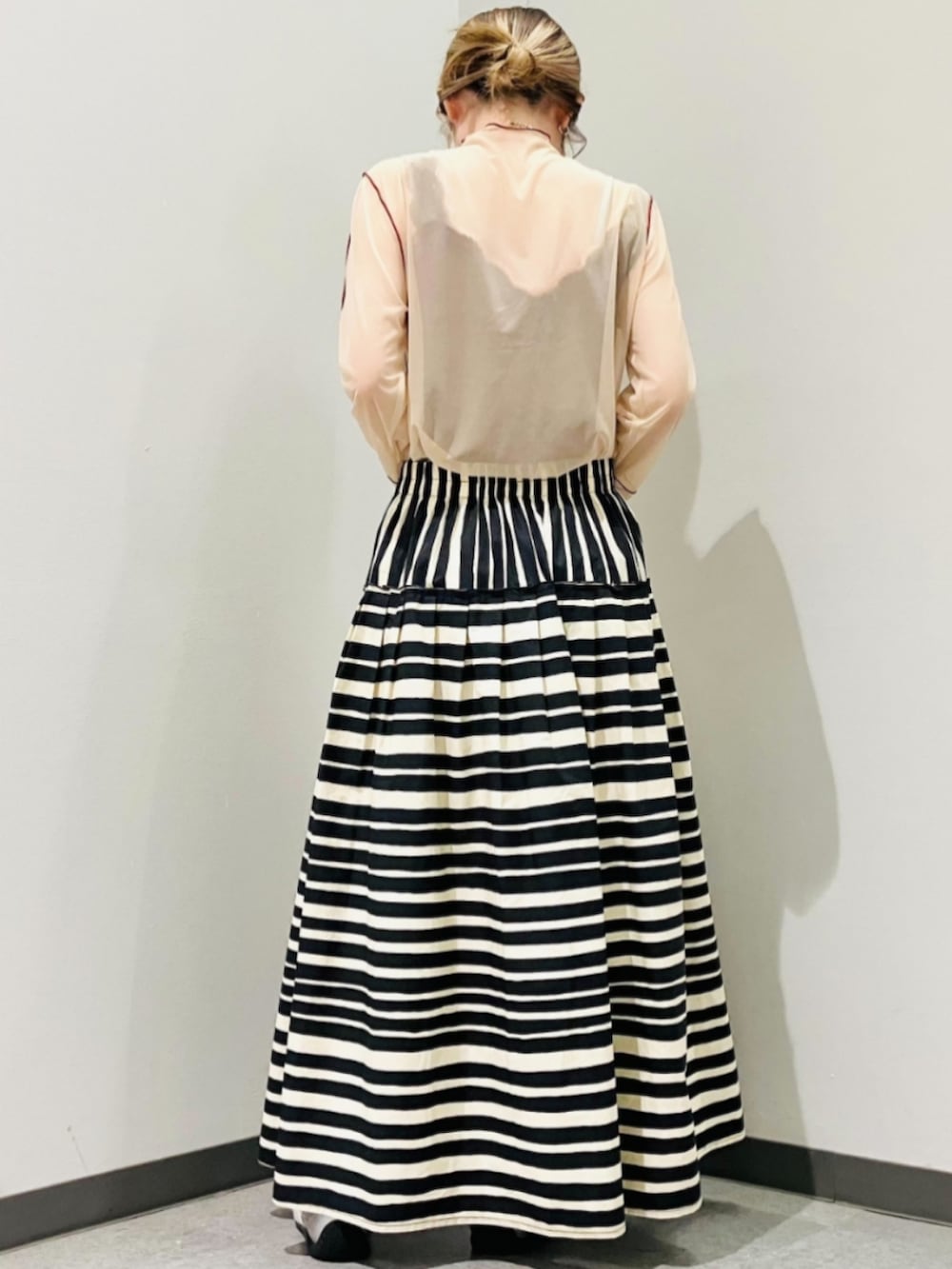 ベージュ系のトートバッグ、ブラック系のスカート、ベージュ系のTシャツ/カットソーを着用したレディースの夏コーディネートの3枚目の写真