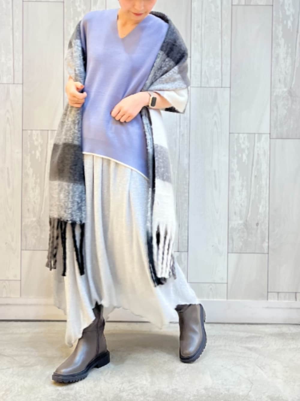 グレー系のブーツ、シルバー系のスカート、ブルー系のニット/セーターを着用したレディースの冬コーディネートの2枚目の写真