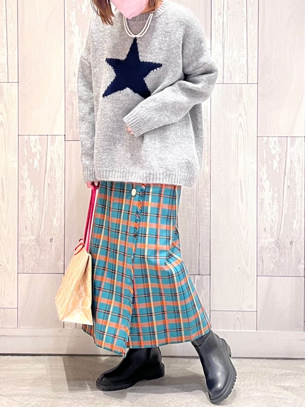 グレー系のニット/セーター、グリーン系のスカート、ブラック系のブーツを着用したレディースの冬コーディネートの2枚目の写真